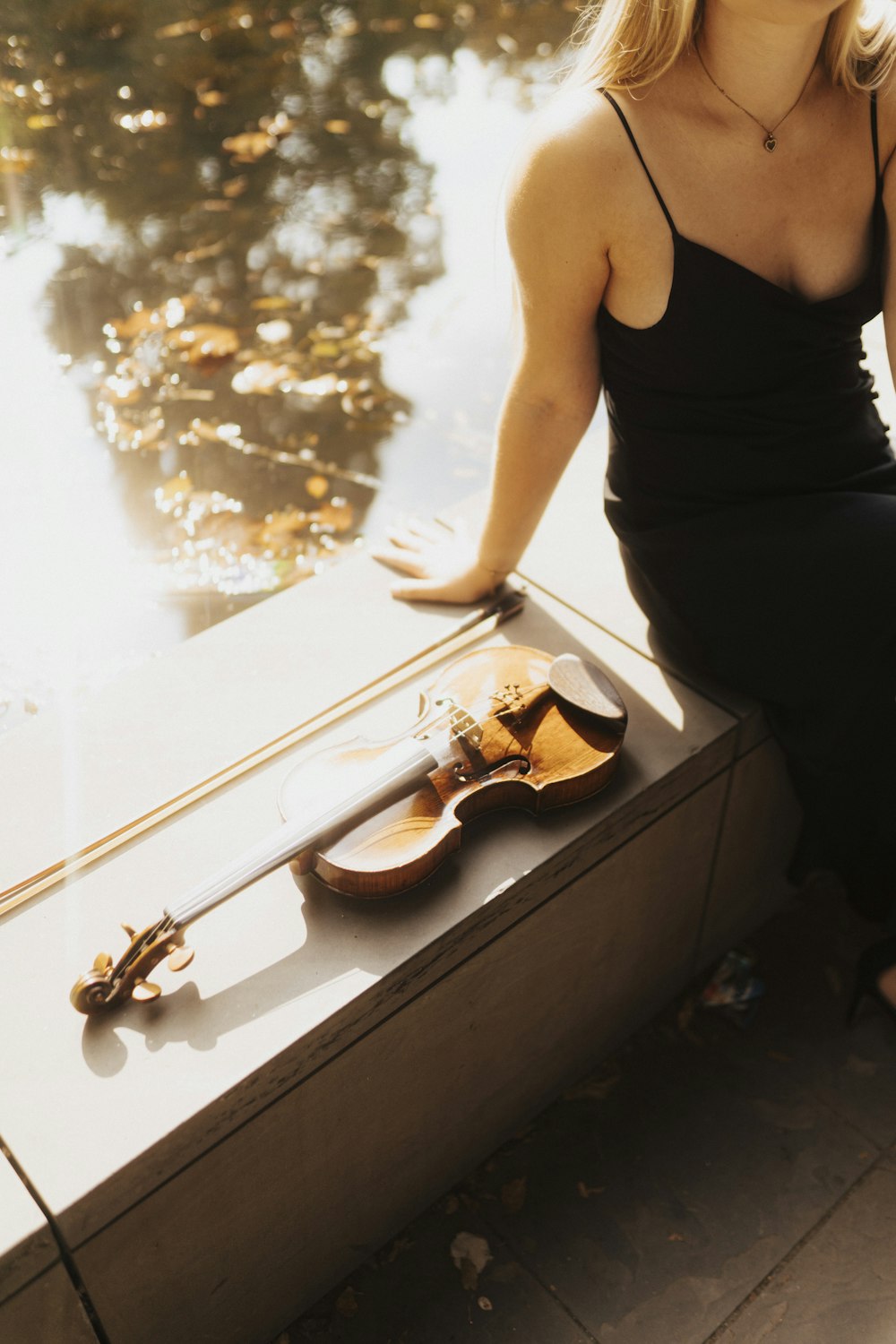 Una mujer sentada en una repisa junto a un violín