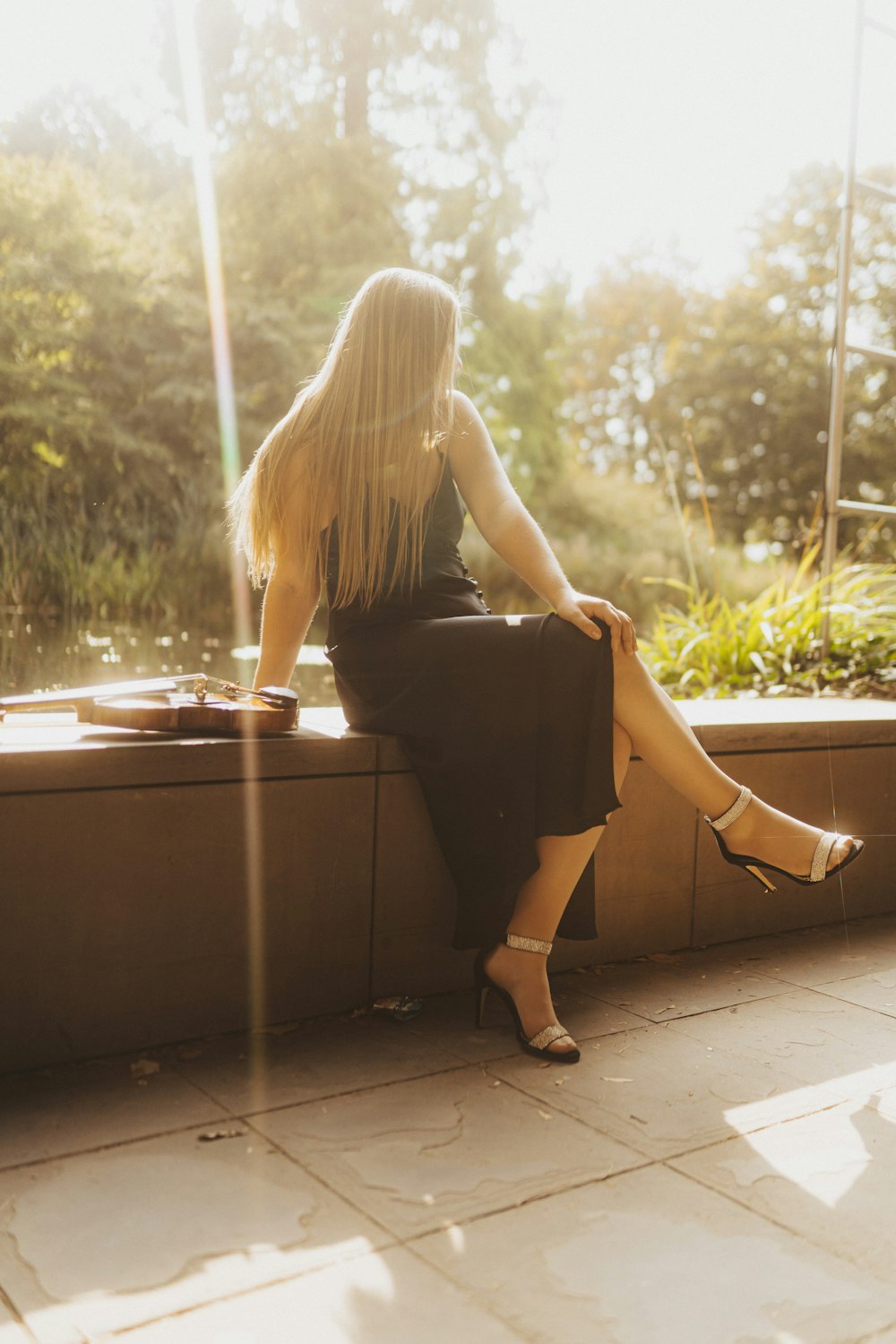 a woman in a black dress sitting on a ledge