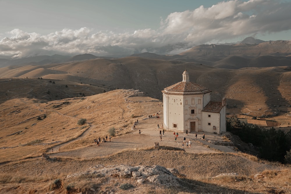 a white church on a hill with mountains in the background