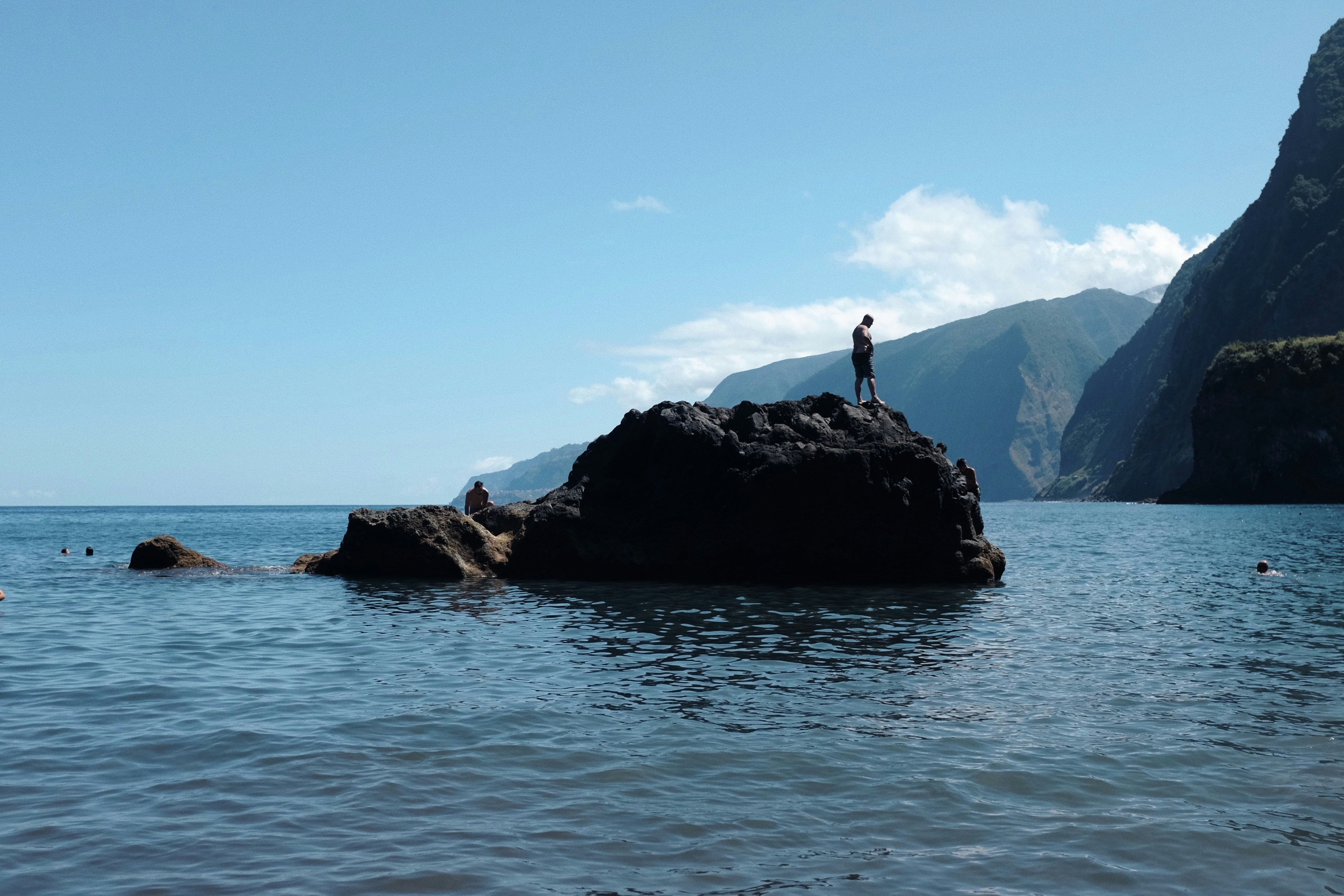 a person standing on a rock in the middle of the ocean