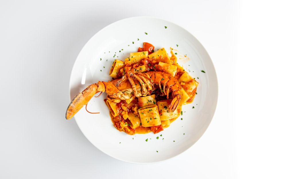 a white plate topped with pasta and shrimp