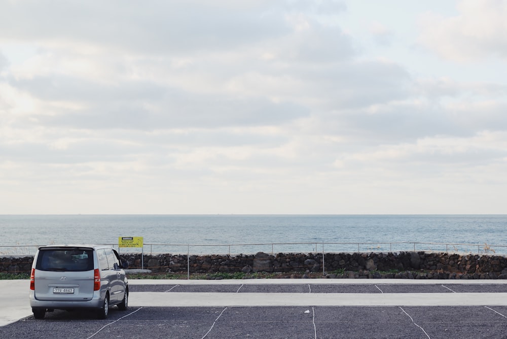 a car parked in a parking lot next to the ocean