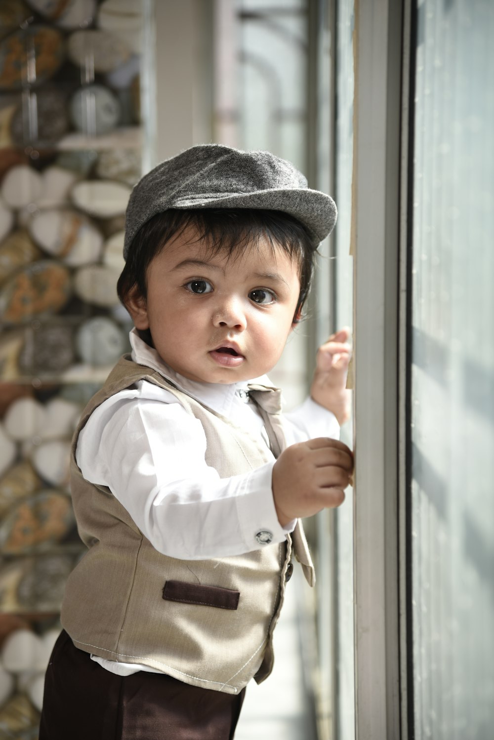 a little boy wearing a hat and vest