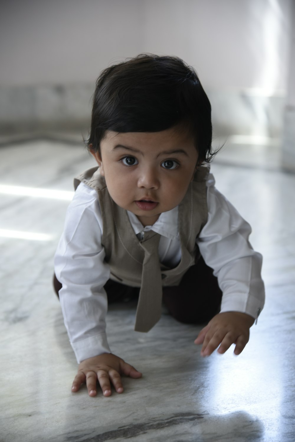 a baby wearing a tie crawling on the floor