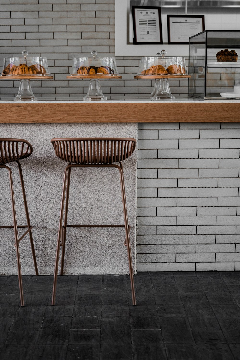 two stools sitting in front of a counter with pastries on it