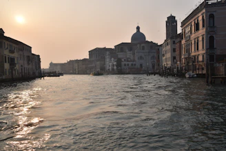 A serene Venetian canal at sunset with historic buildings reflecting in the water.