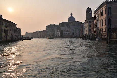 A serene Venetian canal at sunset with historic buildings reflecting in the water.