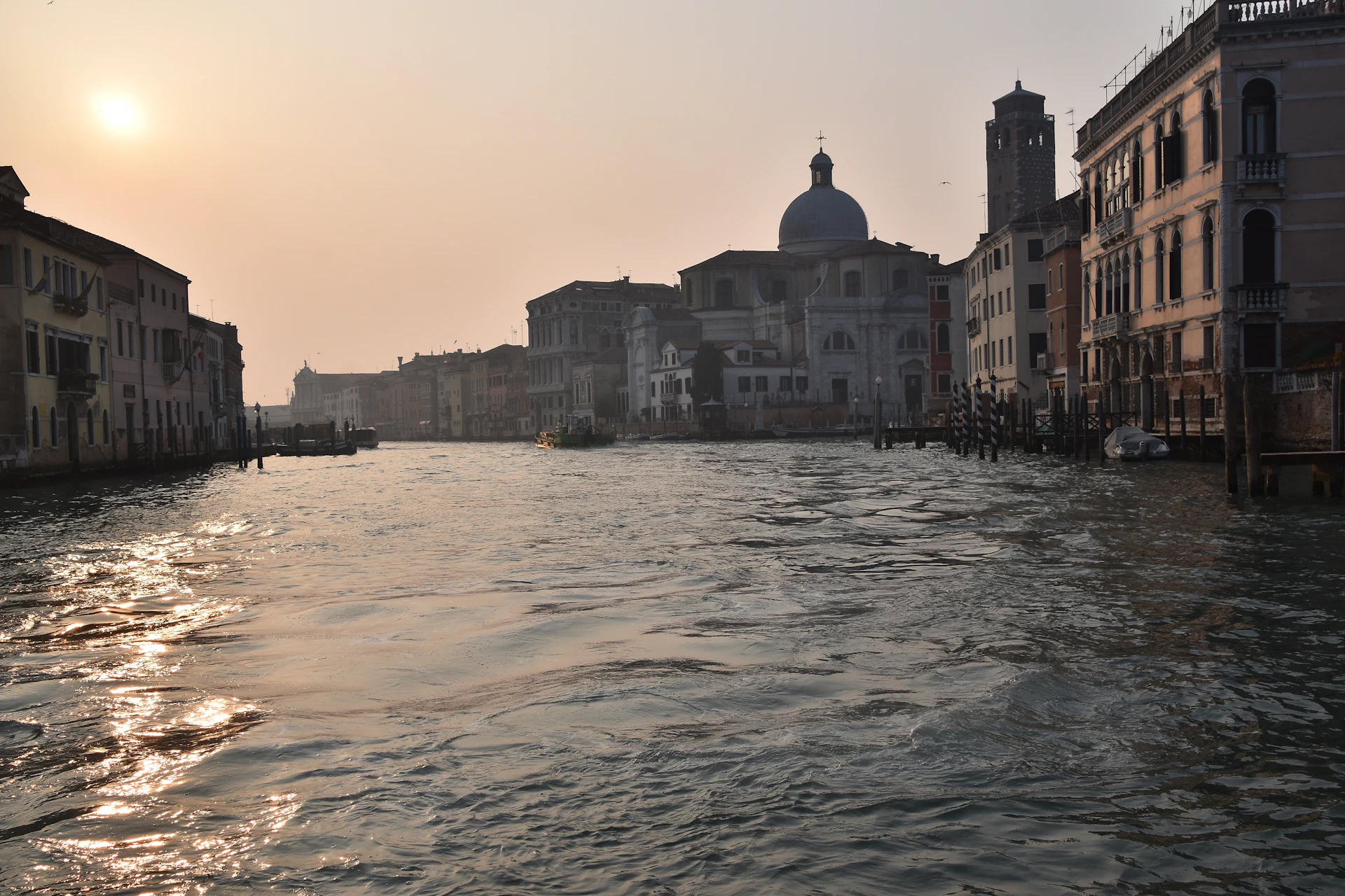 The serene canals of Venice reflecting colorful buildings under a soft sunset sky.
