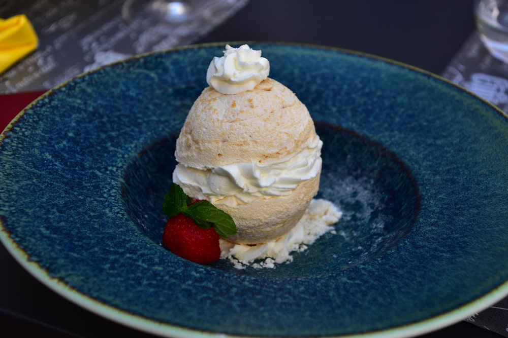 a blue plate topped with a scoop of ice cream and a strawberry