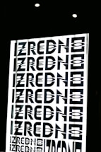 A graphic design featuring the repeated word 'ZREDNO' in bold, stylized black letters. The text appears in a mirrored pattern on a bright white background, creating an optical illusion effect. The image is framed by a dark border with circular lights at the top.