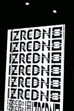 A graphic design featuring the repeated word 'ZREDNO' in bold, stylized black letters. The text appears in a mirrored pattern on a bright white background, creating an optical illusion effect. The image is framed by a dark border with circular lights at the top.