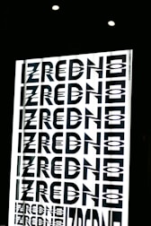 A graphic design featuring the repeated word 'ZREDNO' in bold, stylized black letters. The text appears in a mirrored pattern on a bright white background, creating an optical illusion effect. The image is framed by a dark border with circular lights at the top.