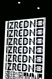A graphic design featuring the repeated word 'ZREDNO' in bold, stylized black letters. The text appears in a mirrored pattern on a bright white background, creating an optical illusion effect. The image is framed by a dark border with circular lights at the top.