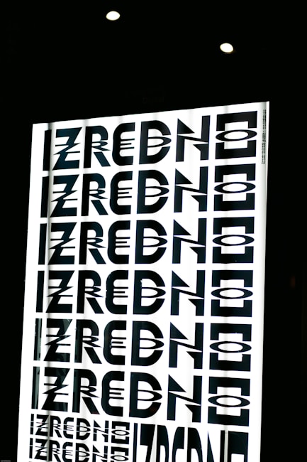 A graphic design featuring the repeated word 'ZREDNO' in bold, stylized black letters. The text appears in a mirrored pattern on a bright white background, creating an optical illusion effect. The image is framed by a dark border with circular lights at the top.