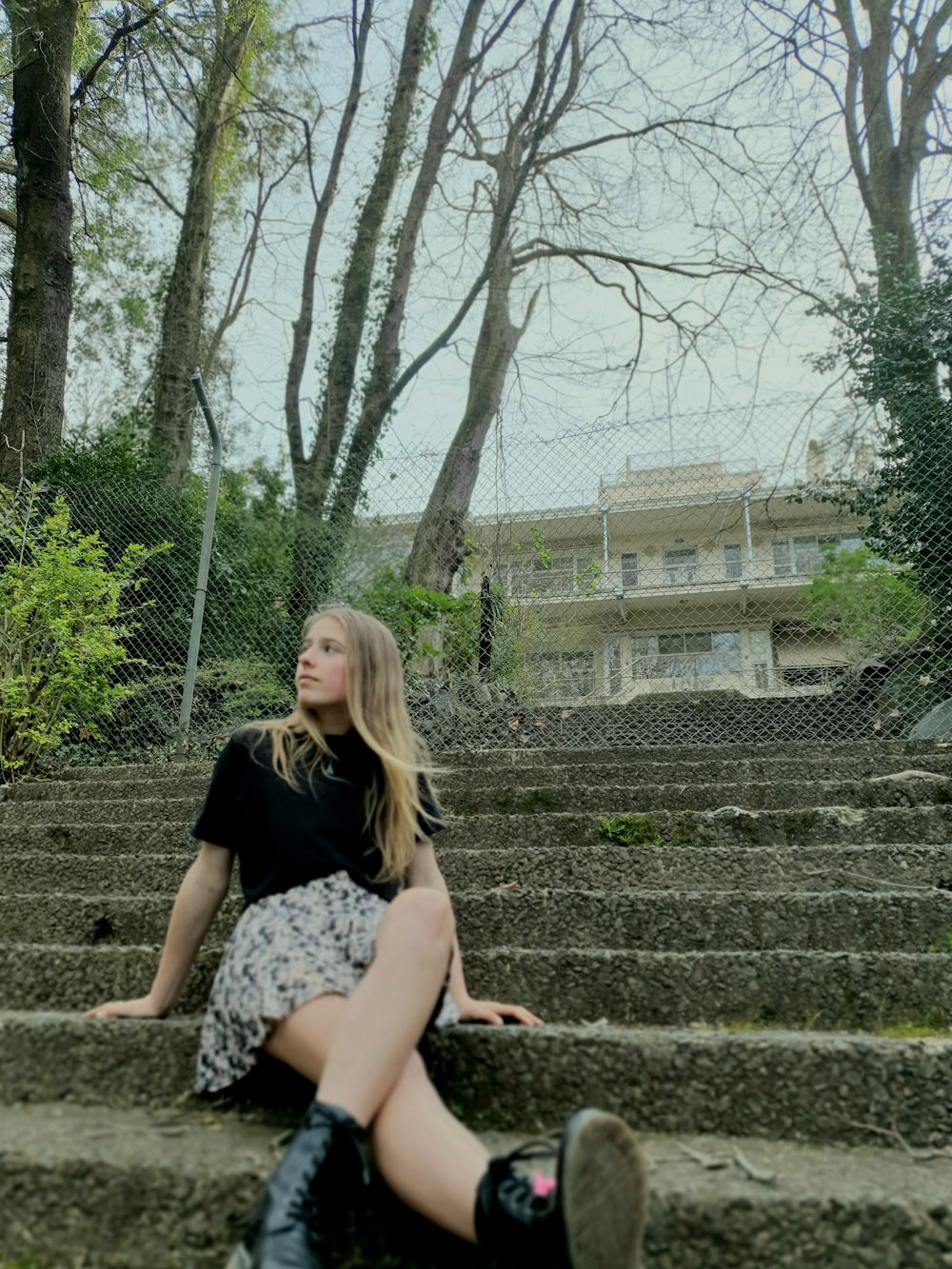 a woman sitting on some steps in front of some trees