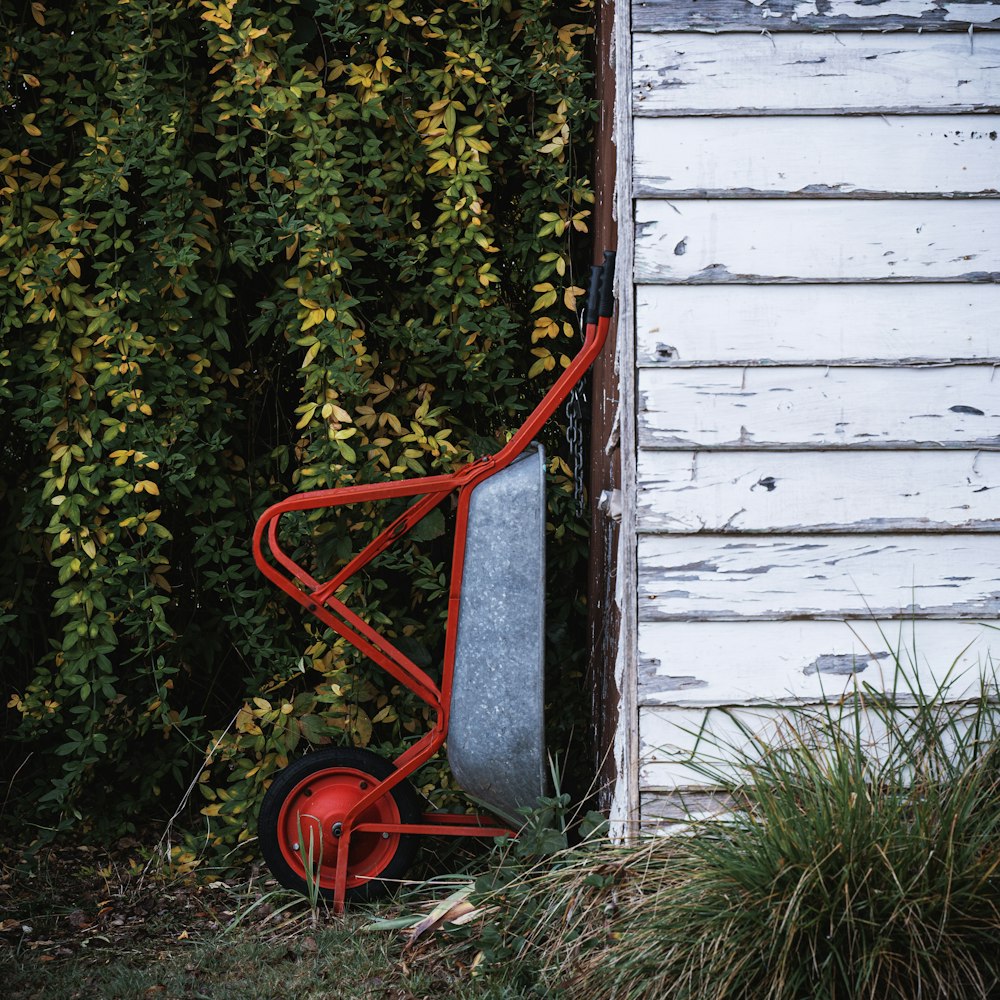 a red wheelbarrow leaning against a white wall