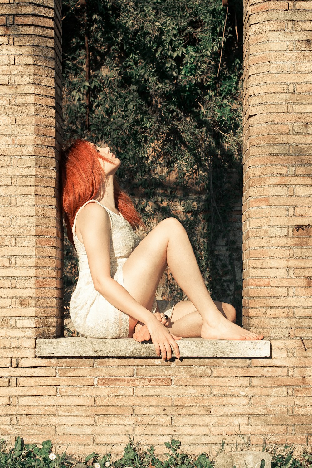 a woman with red hair sitting on a ledge