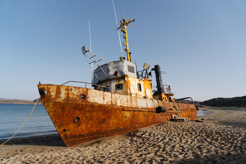 a rusted boat sitting on top of a sandy beach