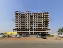 a large building under construction with cars parked in front of it