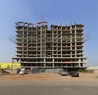 a large building under construction with cars parked in front of it