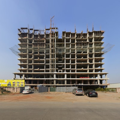 a large building under construction with cars parked in front of it