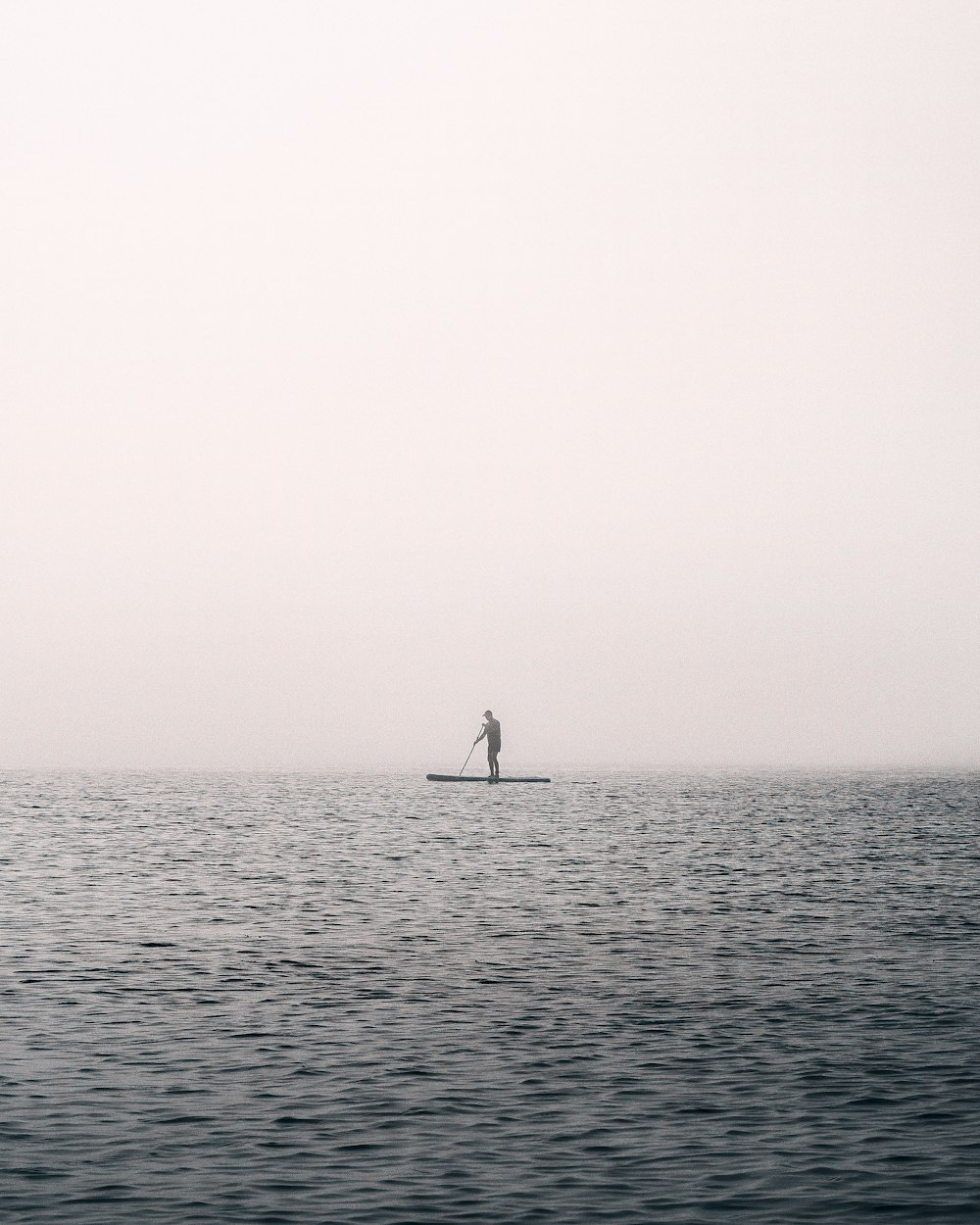 a person standing on a surfboard in the middle of the ocean