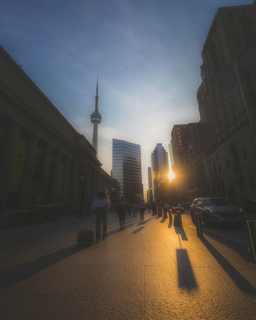 a group of people walking down a street next to tall buildings