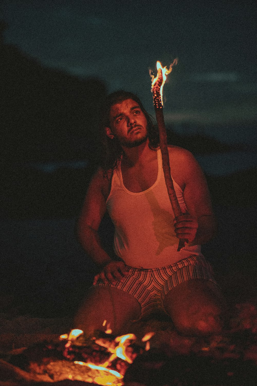 a man sitting on the ground with a stick in his hand