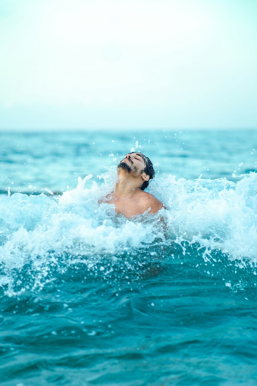 a man swimming in the ocean on a surfboard