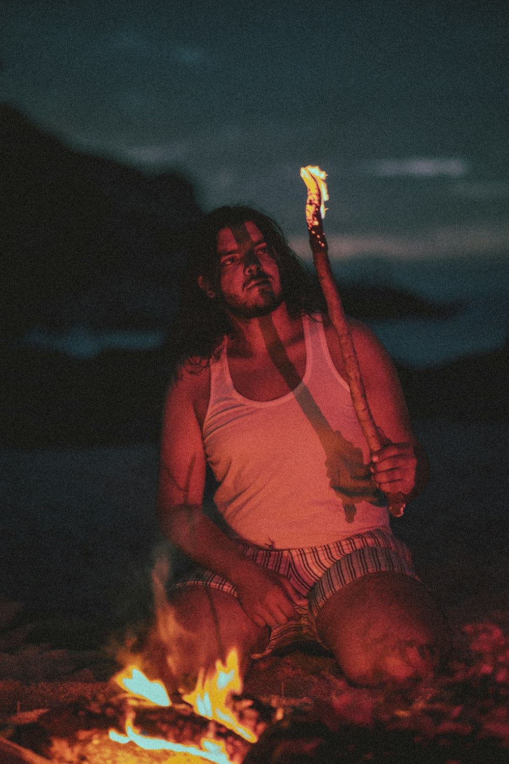 a man sitting on the ground with a stick in his hand