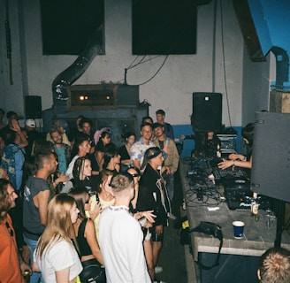 a large group of people in a party room where a dj is playing