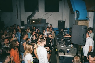 a large group of people in a party room where a dj is playing