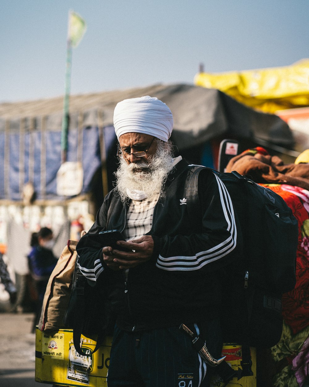 a man with a white turban is looking at his cell phone