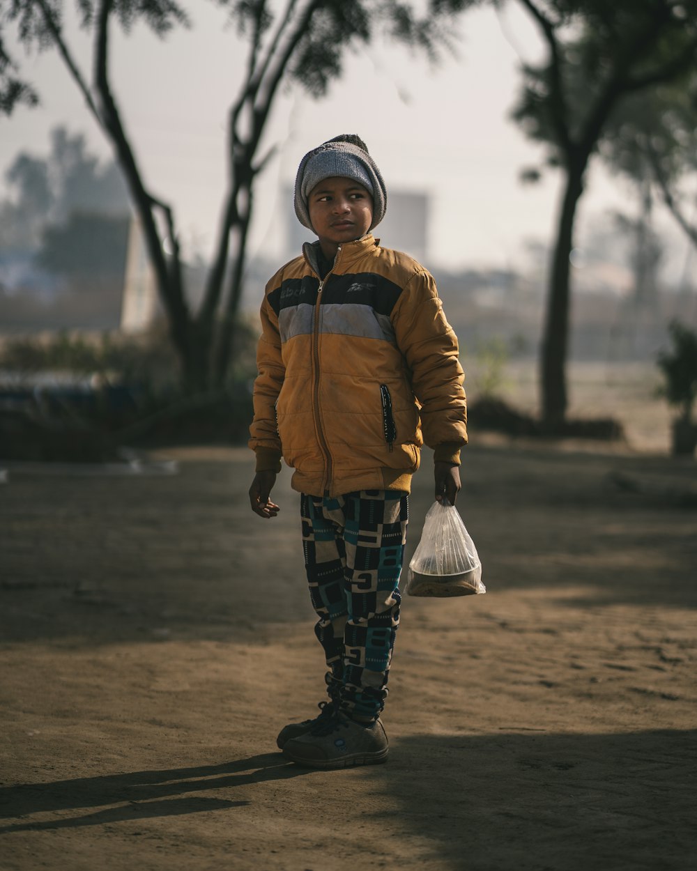 a young boy in a yellow jacket carrying a bag