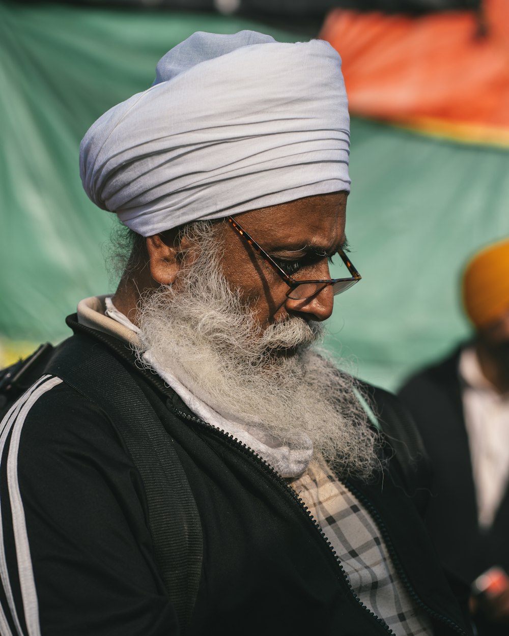 a man with a white turban is looking at his cell phone