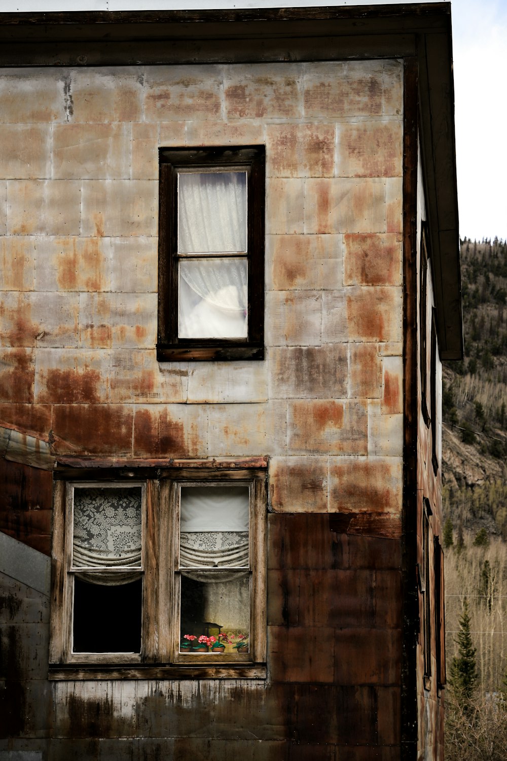 a run down building with a window and curtains