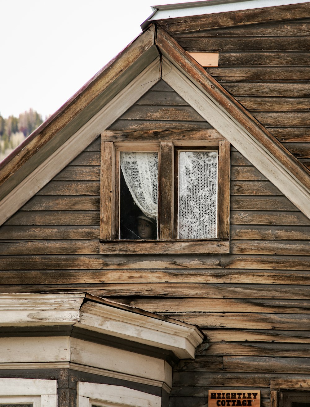 un edificio de madera con una ventana y un letrero en el costado