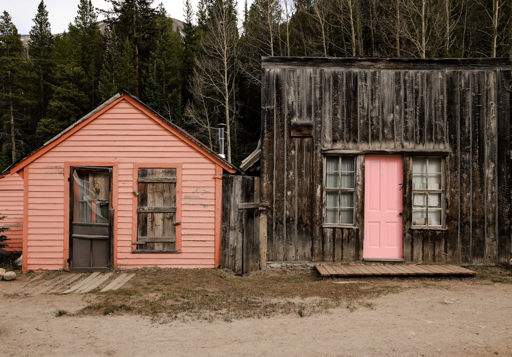 two old wooden buildings with pink doors and windows