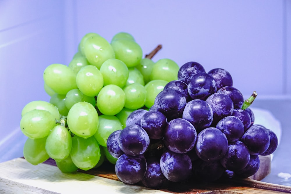 um cacho de uvas sentado em cima de uma tábua de corte