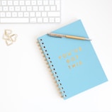 a notepad with a pen on top of it next to a keyboard