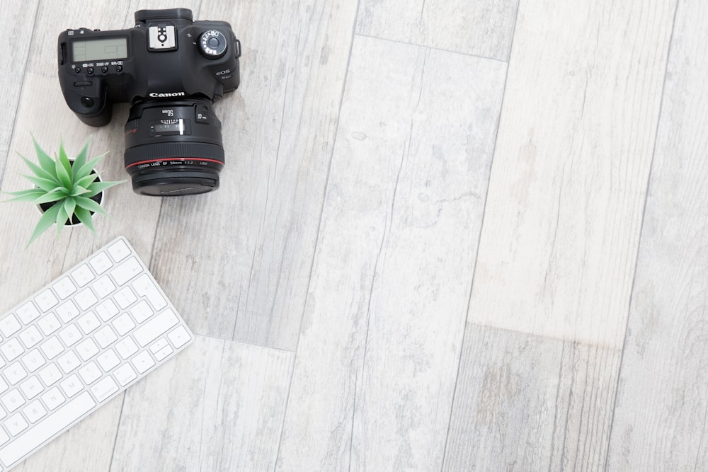 a camera and a keyboard on a wooden floor