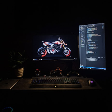 An industrial-style workspace with multiple screens displaying 3D design software and motorcycle models.