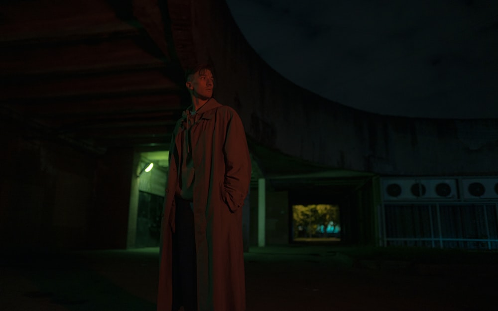 a man in a long coat standing in the dark