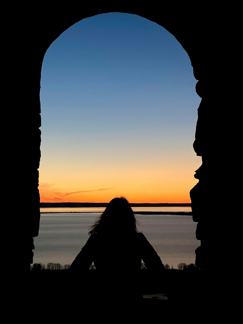 una silhouette di una persona seduta davanti a una finestra