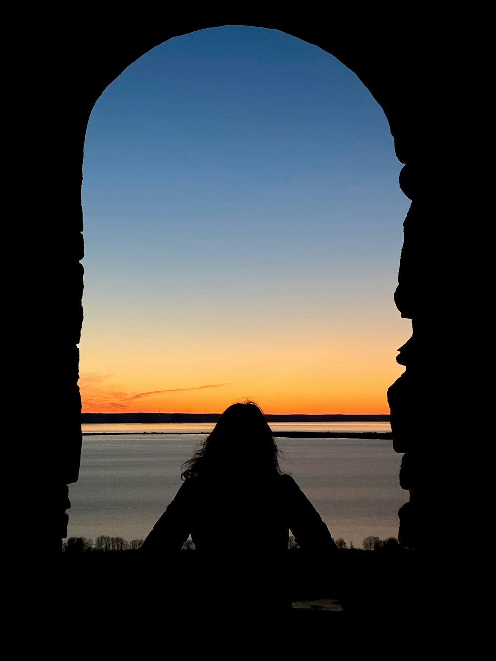 a silhouette of a person sitting in front of a window