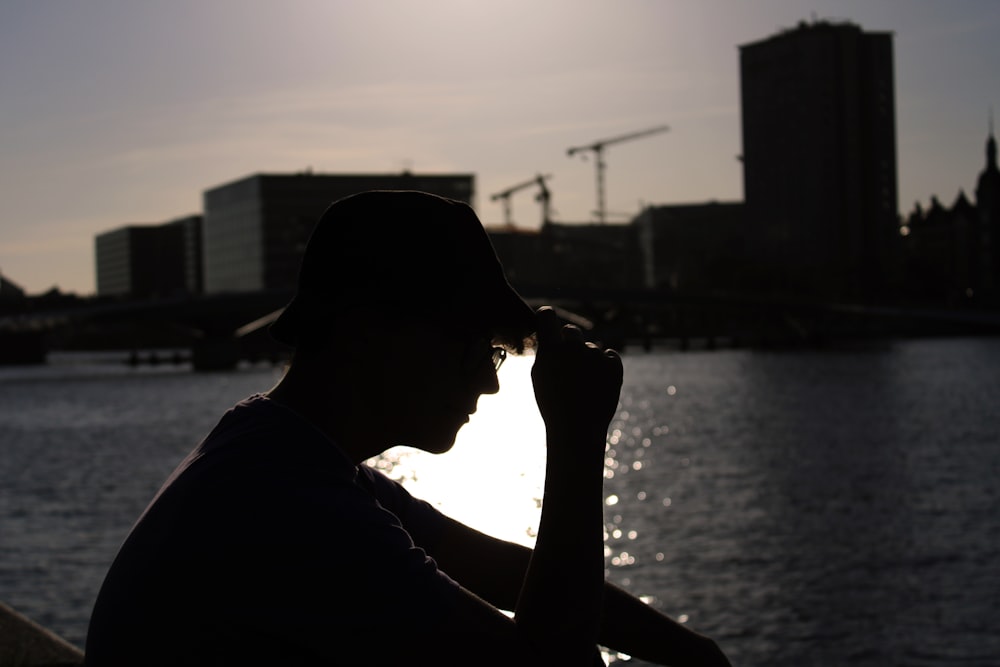 a silhouette of a man sitting on a bench in front of a body of water