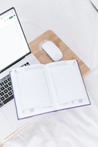 Neutral-toned study setup with a closed notebook and pen beside a laptop.