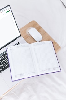 Compact travel mouse resting beside a laptop and notebook
