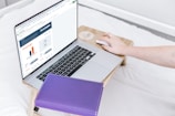 a person using a laptop computer on a bed