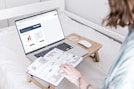 a person sitting on a bed with a laptop